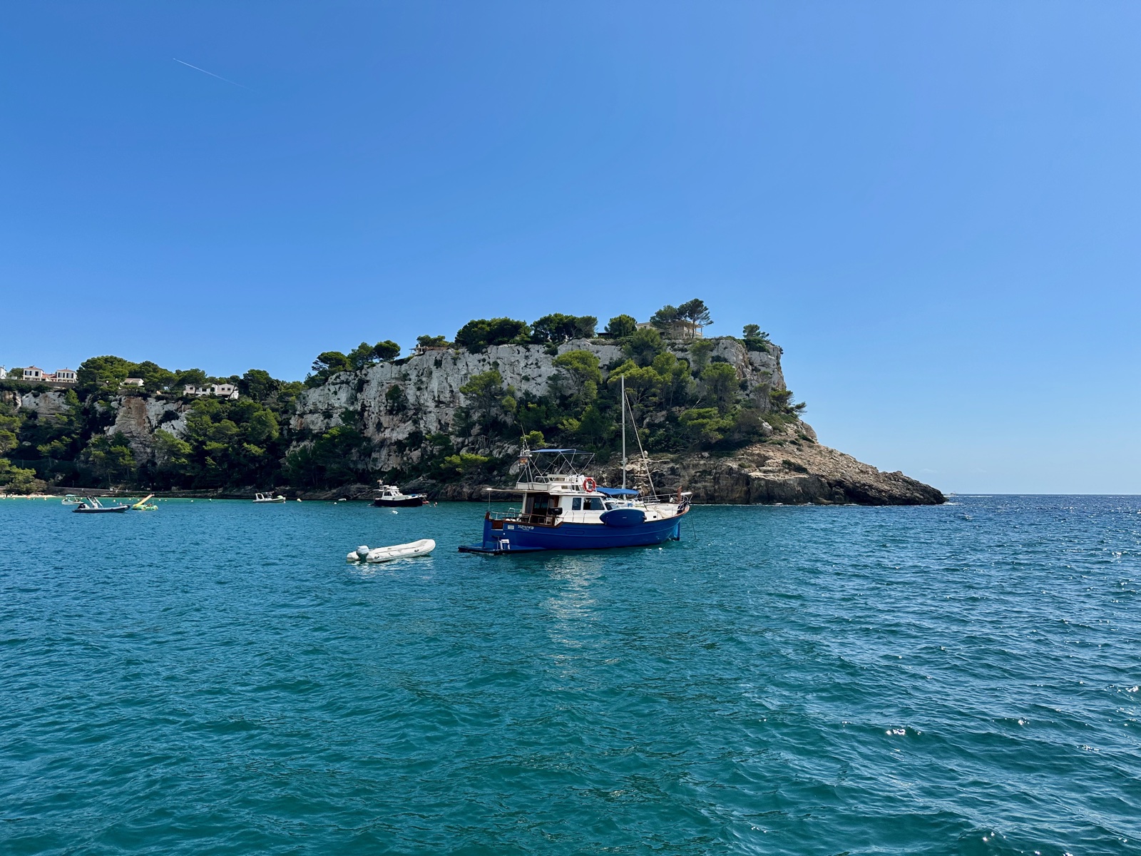 Blue fishing boat moored in the calm turquoise waters of the bay
